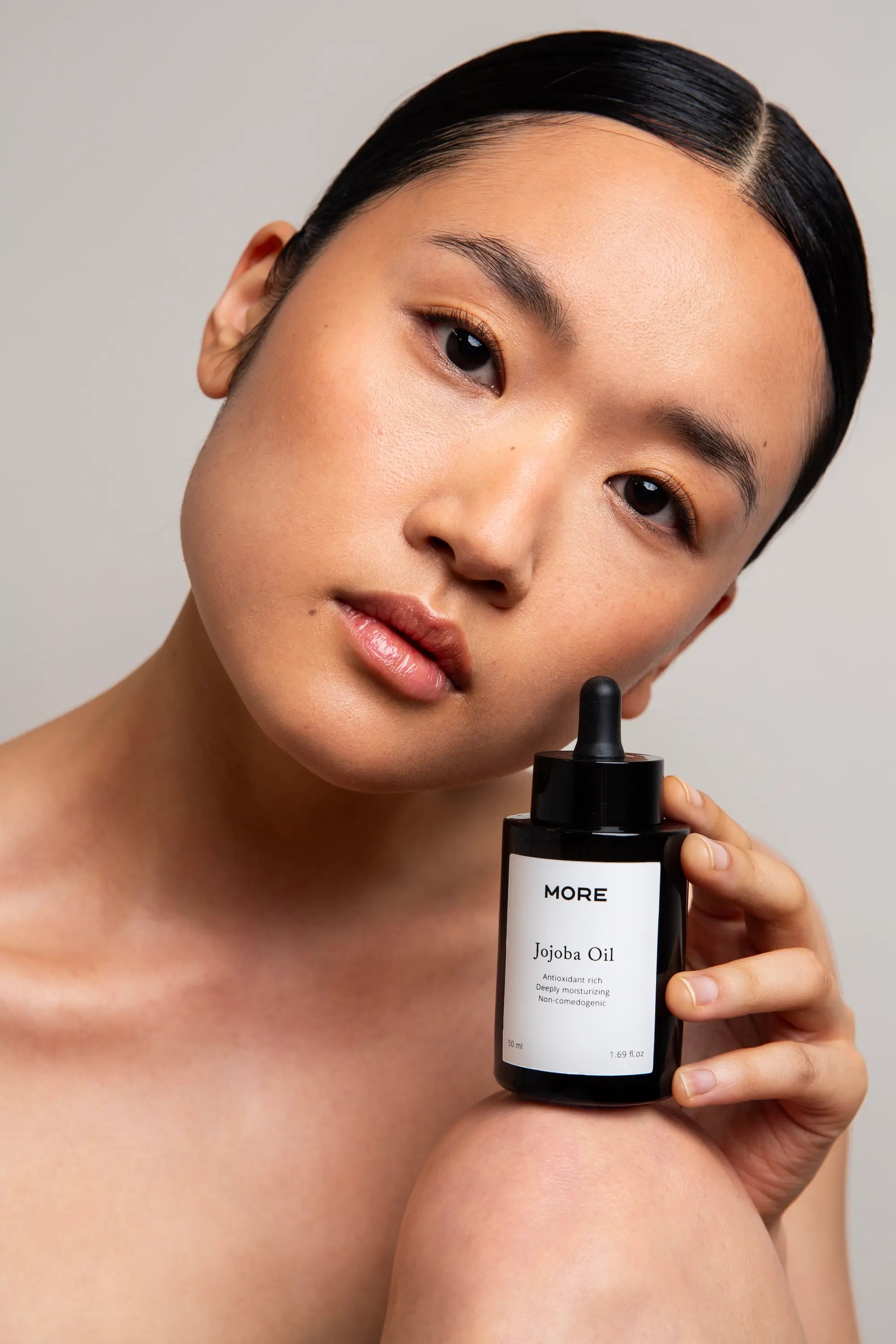 Model houdt More Natural Jojoba Oil 50 ml vast voor dagelijkse huidverzorging